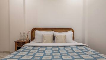 A bed with a patterned bedspread, a wooden headboard, and two pillows.