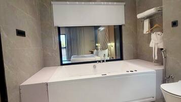 Une salle de bain moderne dotée d’une grande baignoire, d’une douche séparée et de toilettes.