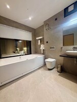 Un baño moderno con una bañera grande, un inodoro y un lavamanos.