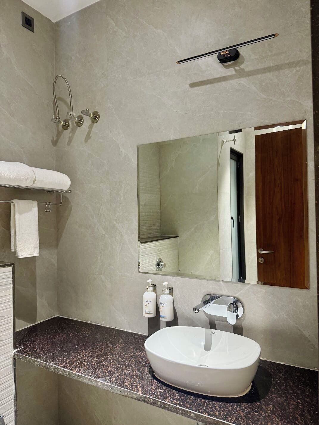 A bathroom with a white sink, a mirror, a towel rack, and a showerhead.