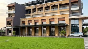 Um hotel moderno com telhado plano, várias varandas e um gramado bem cuidado à frente.