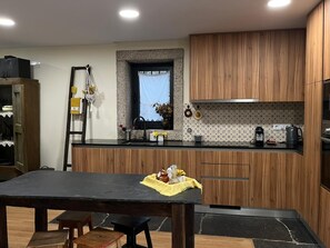 A modern kitchen with wooden cabinets, a stone backsplash, and a window above the sink. - Country House - Casa do Mel, PR6Rio Marão trail, Ansiães village, Serra do Marão (Amarante)