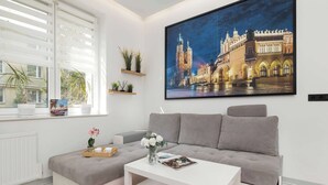 A modern living room with a grey sofa, a white coffee table, and a large framed picture of a building. - Cozy Studio for Two | 800 m from Blonia Krakowskie (Kraków)