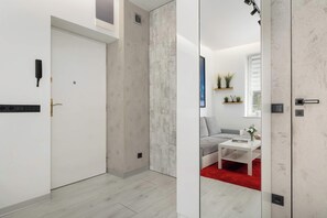 A modern hotel room with a white door, a red carpet, a grey sofa, and a white coffee table. - Cozy Studio for Two | 800 m from Blonia Krakowskie (Kraków)