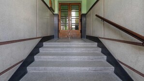 A staircase with a wooden handrail, a door with glass panels, and a green wall. - Cozy Studio for Two | 800 m from Blonia Krakowskie (Kraków)