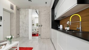 A modern kitchen with white cabinetry, a black countertop, and a yellow faucet. - Cozy Studio for Two | 800 m from Blonia Krakowskie (Kraków)