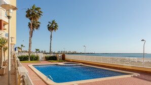 Une piscine avec vue sur la mer, des palmiers et une clôture blanche.