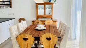 Een eetkamer met een houten tafel, zes stoelen, een kast en een hanglamp.