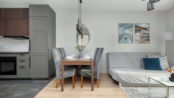 A modern kitchen with grey cabinets, a dining table with chairs, a sofa, and a lamp.