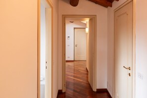 A hallway with wooden flooring, white walls, and a door at the end. - Cozy penthouse in the heart of Via Mazzini (Verona)