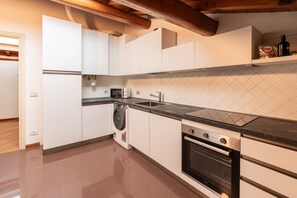 A modern kitchen with white cabinets, a built-in oven, a microwave, and a dishwasher. - Cozy penthouse in the heart of via Mazzini (Verona)