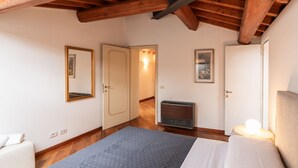 Ein Schlafzimmer mit einem Bett, einem Heizkörper, einer Tür und einem an der Wand befestigten Spiegel.