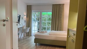 A bedroom with a bed, a desk, a chair, and a window with curtains. - The Loft (Münster)