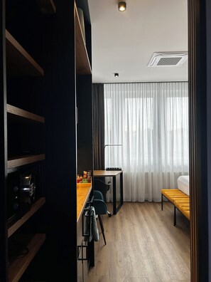 A modern room with a wooden floor, a desk with a chair, a bench, and a bed. - The Loft (Münster)