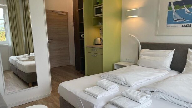 A hotel room with a bed, a desk, a chair, a wardrobe, a bathroom, and a kitchenette. - The Loft (Münster)