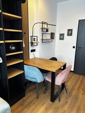 A modern room with a wooden dining table, two chairs, a black bookshelf, and a wall-mounted TV. - The Loft (Münster)