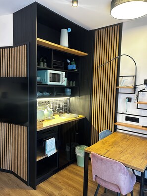 A compact kitchen with a microwave, kettle, and various utensils. - The Loft (Münster)