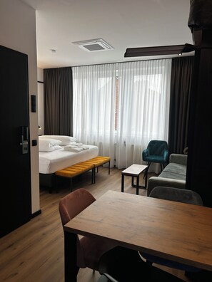 A hotel room with a bed, a wooden table, a bench, a chair, and a sofa. - The Loft (Münster)