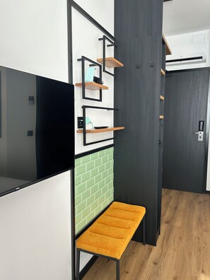A modern interior with a flat-screen TV, a bench, and a wall-mounted shelf unit. - The Loft (Münster)