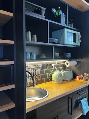 A modern kitchen with a built-in microwave, kettle, and toaster. There are shelves above the counter holding various kitchen items. - The Loft (Münster)