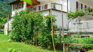 Un bâtiment à deux étages doté d’un balcon, entouré de verdure.