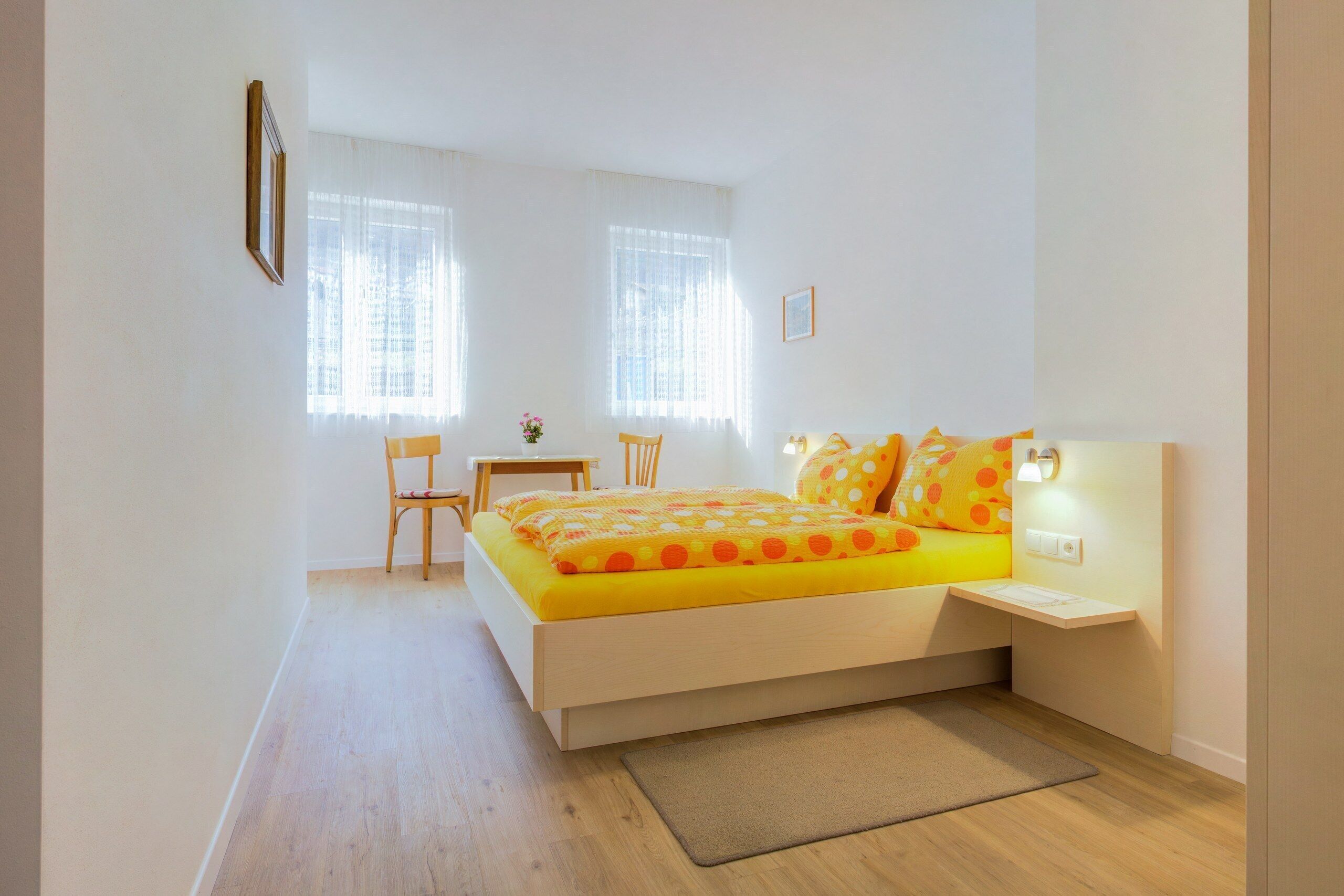 Ein Schlafzimmer mit einem Bett, einem Schreibtisch, zwei Stühlen und einem kleinen Tisch.