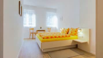 Ein Schlafzimmer mit einem Bett, einem Schreibtisch, zwei Stühlen und einem kleinen Tisch.