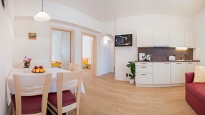 Ein modernes Wohnzimmer mit Essbereich, einer Küche und einem an der Wand befestigten Fernseher.