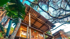 Une maison en bois dotée d’un balcon, entourée d’arbres.