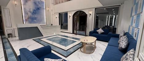 A spacious living area with a pool, blue sofas, and a modern design.