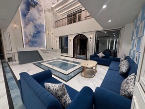 Un vaste espace de vie avec une piscine, des canapés bleus et un design moderne.