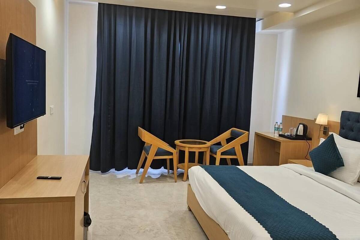 Une chambre d’hôtel équipée d’un lit, d’un bureau, d’une chaise, d’une télévision et d’un ventilateur de plafond.