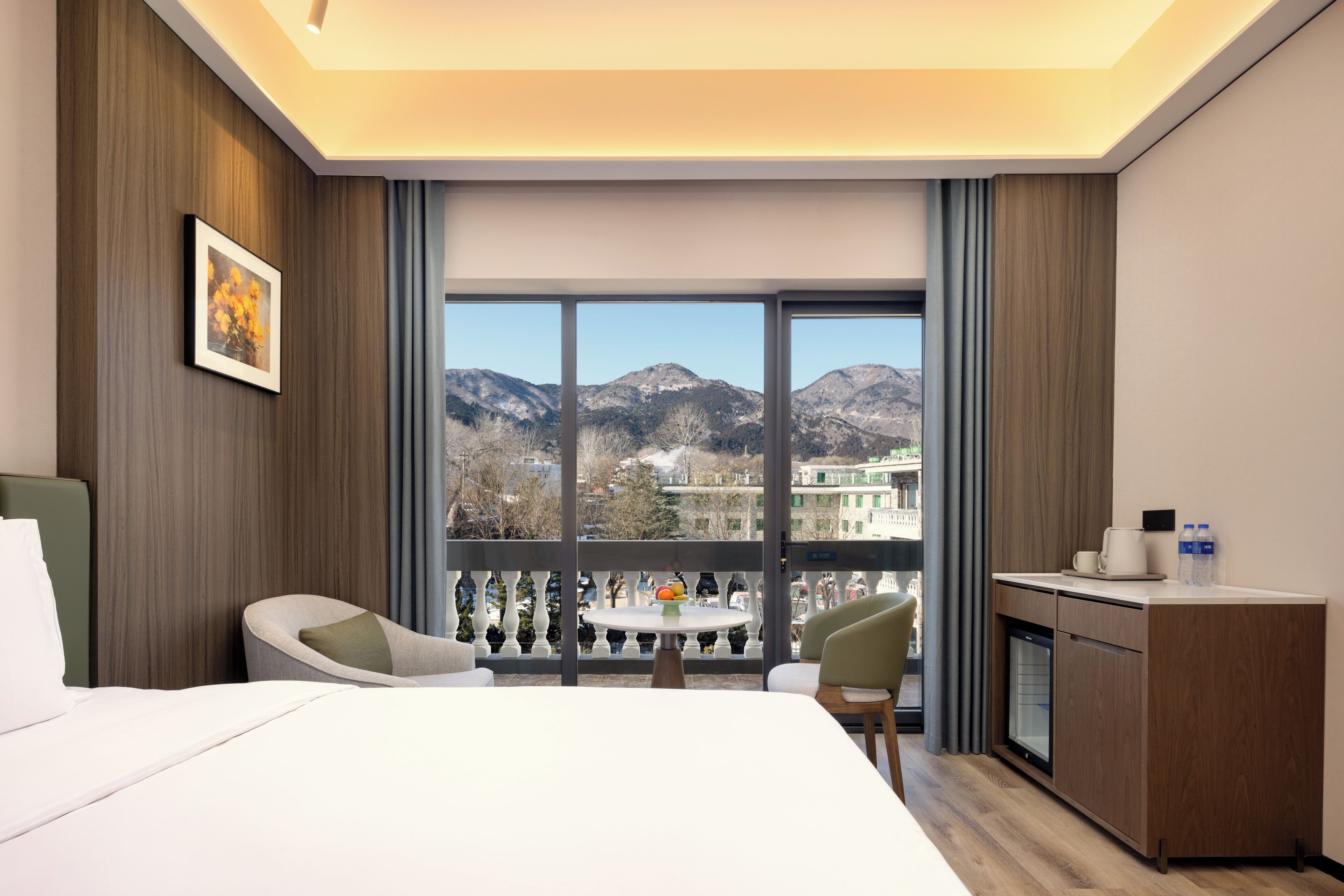 Ein Hotelzimmer mit Bett, Schreibtisch, Stuhl, Tisch und Balkon mit Blick auf die Berge.