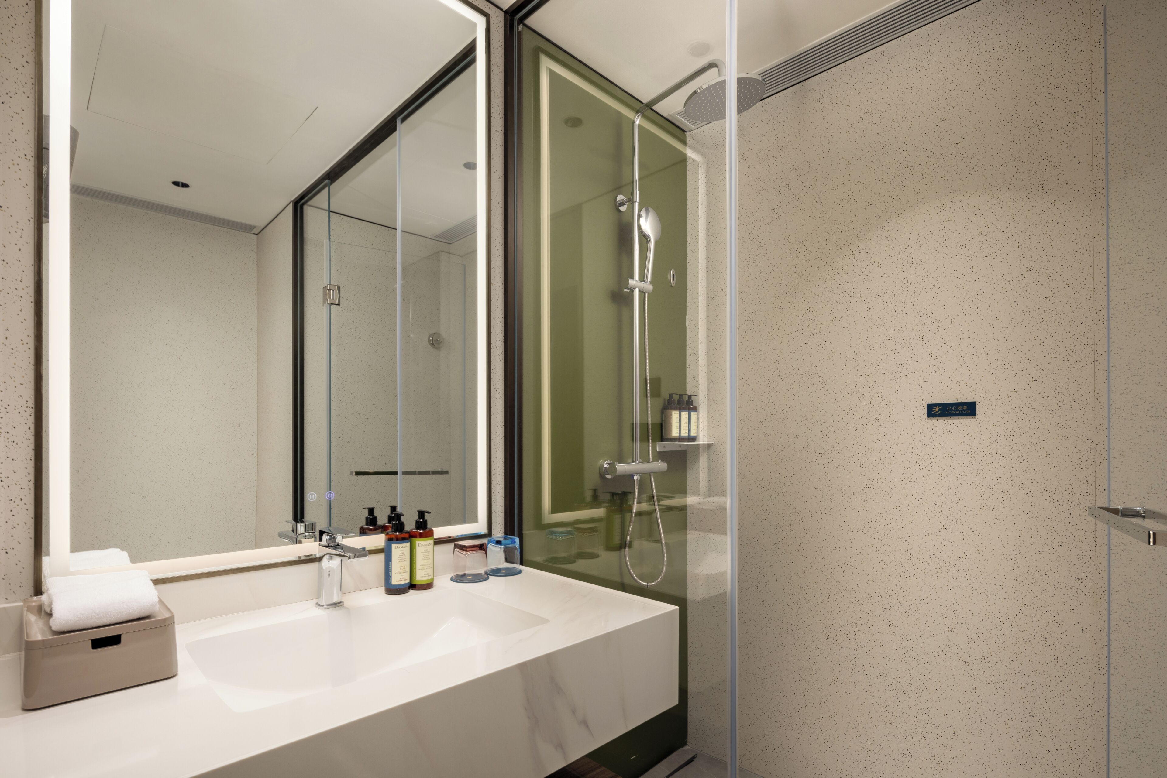 A modern bathroom with a large mirror, a white sink, and a glass-enclosed shower area.