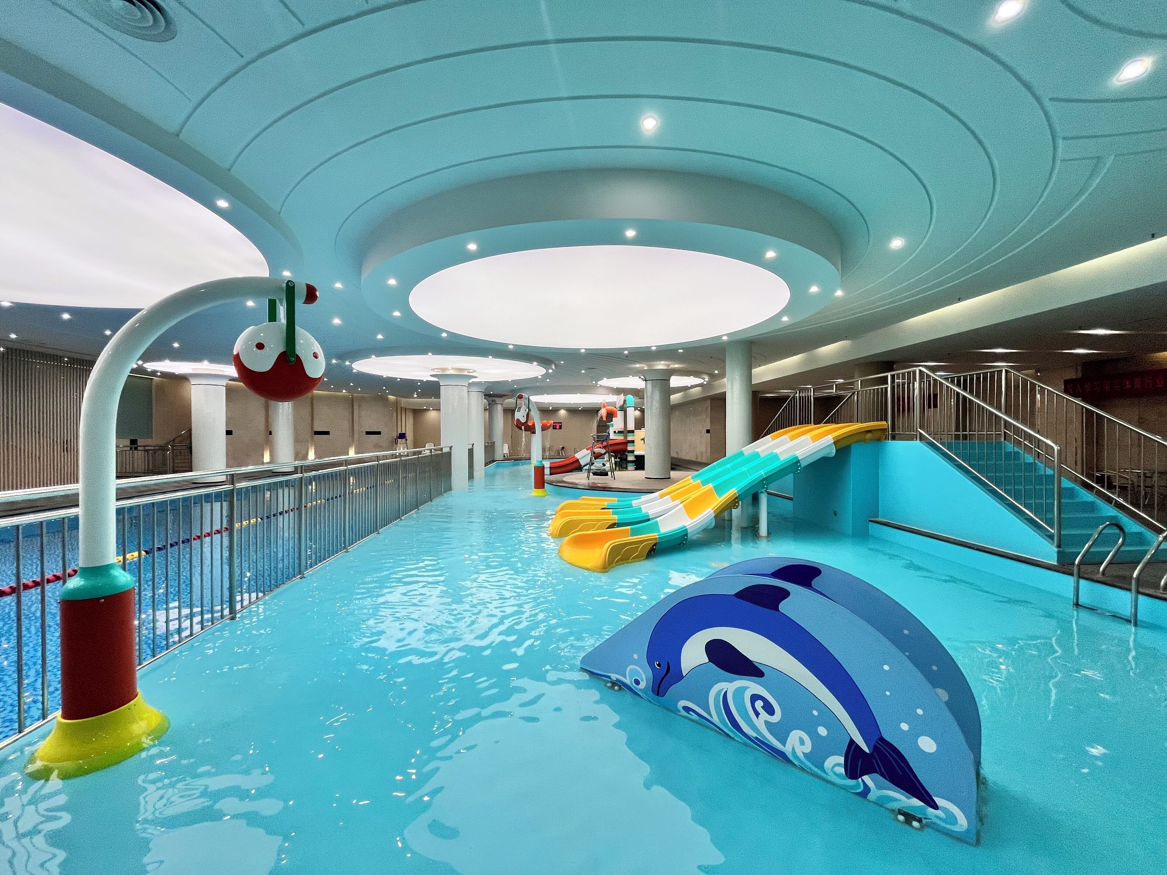 An indoor water park with slides and a dolphin-themed pool area.