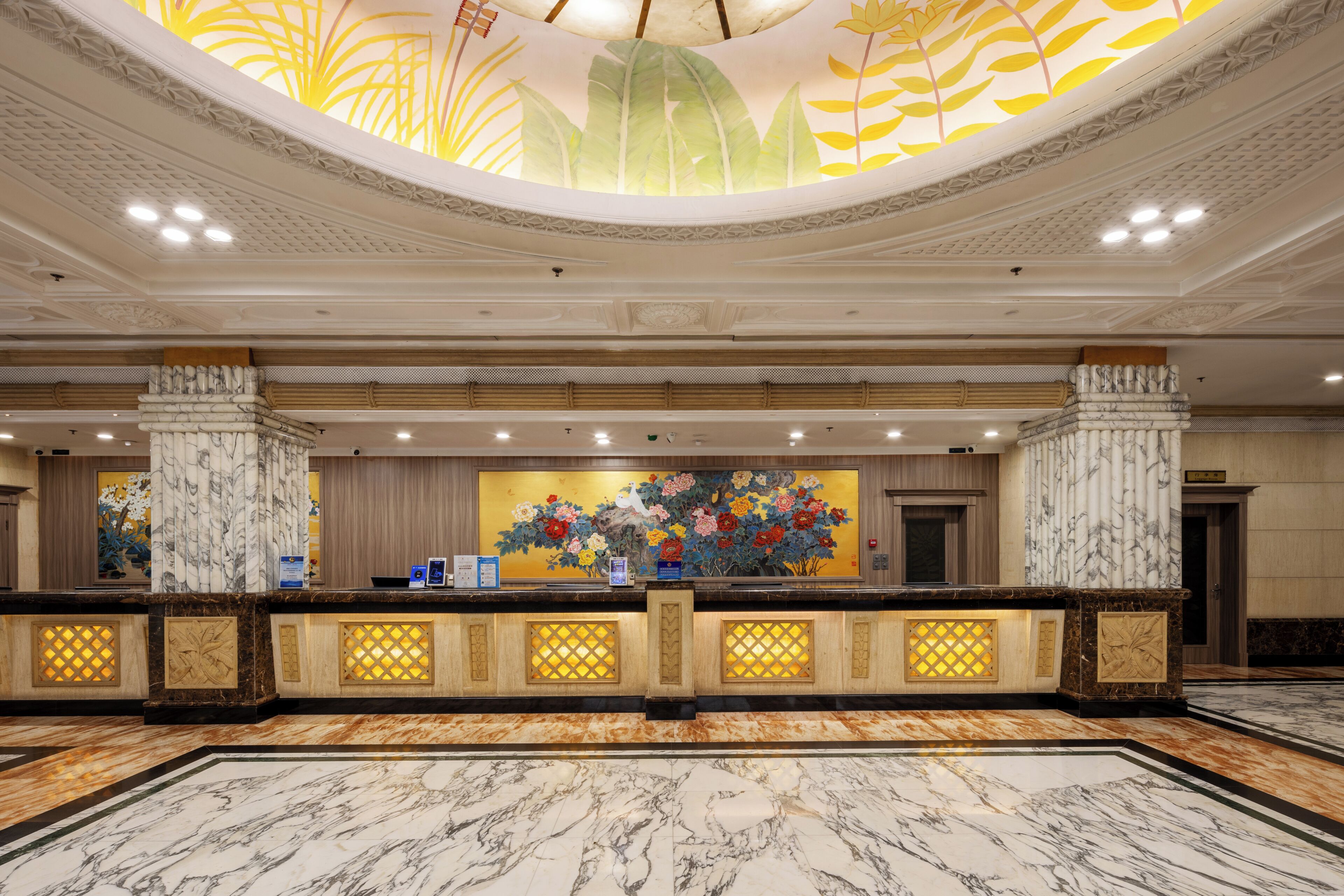 Een hotel receptie met een marmeren vloer, een groot bloemen schilderij en een modern plafondontwerp.