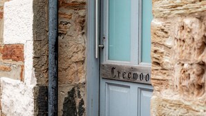 Una porta con il nome 'Creemoo' intagliato, incastonata in un muro di pietra con stipite in legno.