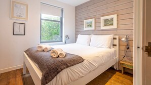 Una camera da letto moderna con un letto grande, pannelli in legno a parete, una finestra con vista e opere d'arte incorniciate.