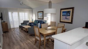 Een moderne hotelkamer met een zithoek, een loungeset, een houten vloer en een plafondventilator.