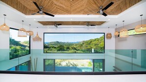 Een modern interieur met grote ramen, plafondventilatoren en rieten hanglampen.
