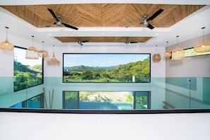 A modern interior with large windows, ceiling fans, and wicker pendant lights. - Stunning View Retreat in Mar Vista, Pool, Unique Design (Santa Cruz)