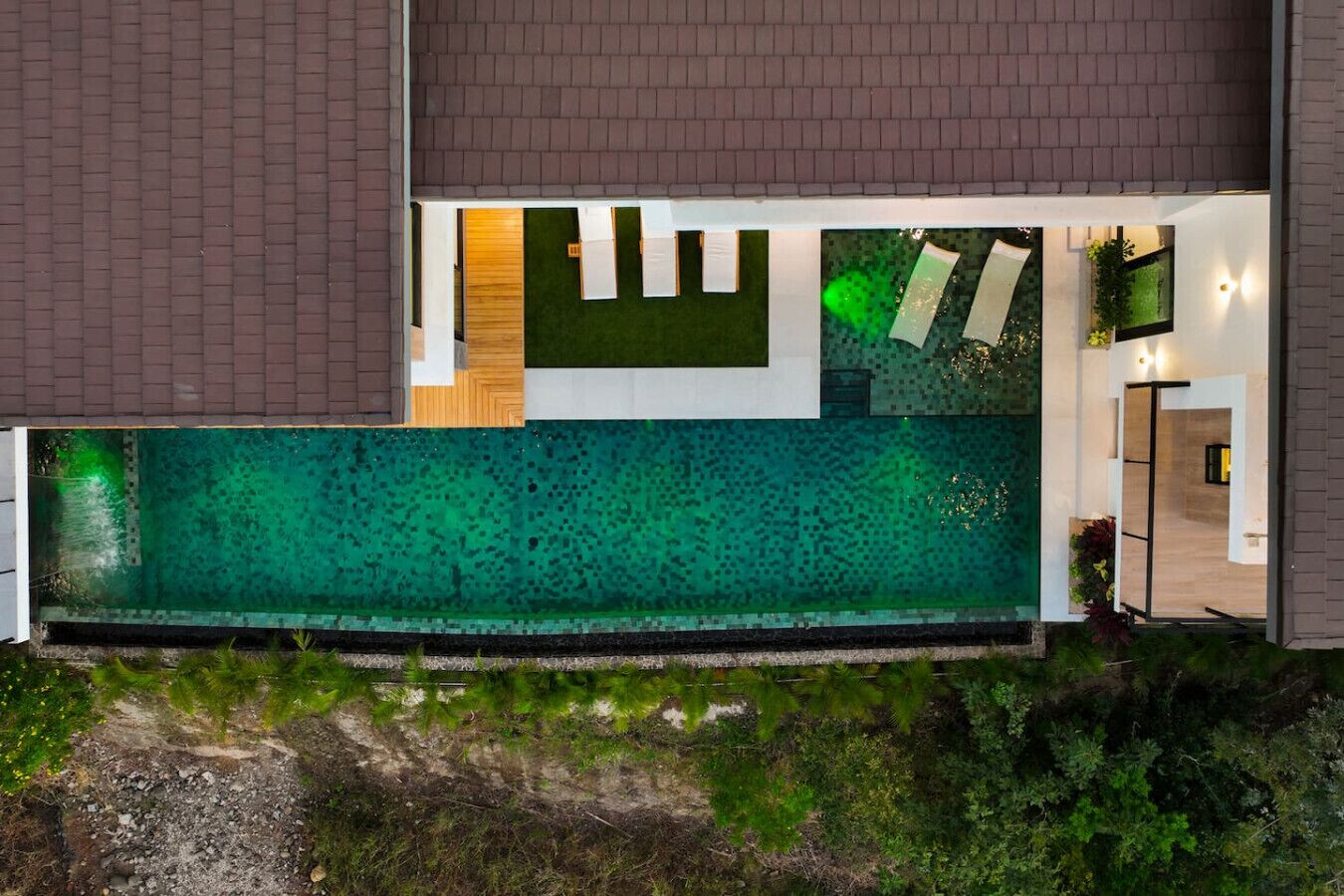 A modern house with a large swimming pool, a wooden deck, and a well-maintained garden.