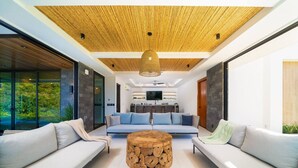 Een moderne woonkamer met een houten plafond, een ronde salontafel en een zithoek.