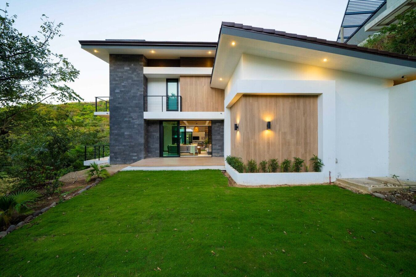 A modern two-story house with a well-maintained lawn, a visible entrance, and a large window on the ground floor.