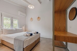 Quarto moderno com cama, mesas de cabeceira, ar condicionado fixado na parede e uma janela.
