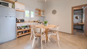 Een moderne keuken met witte kasten, een ingebouwde oven, een ronde eettafel met stoelen en een kleine potplant.