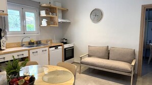 Een kleine keuken met een eethoek, een bank en een klok aan de muur.