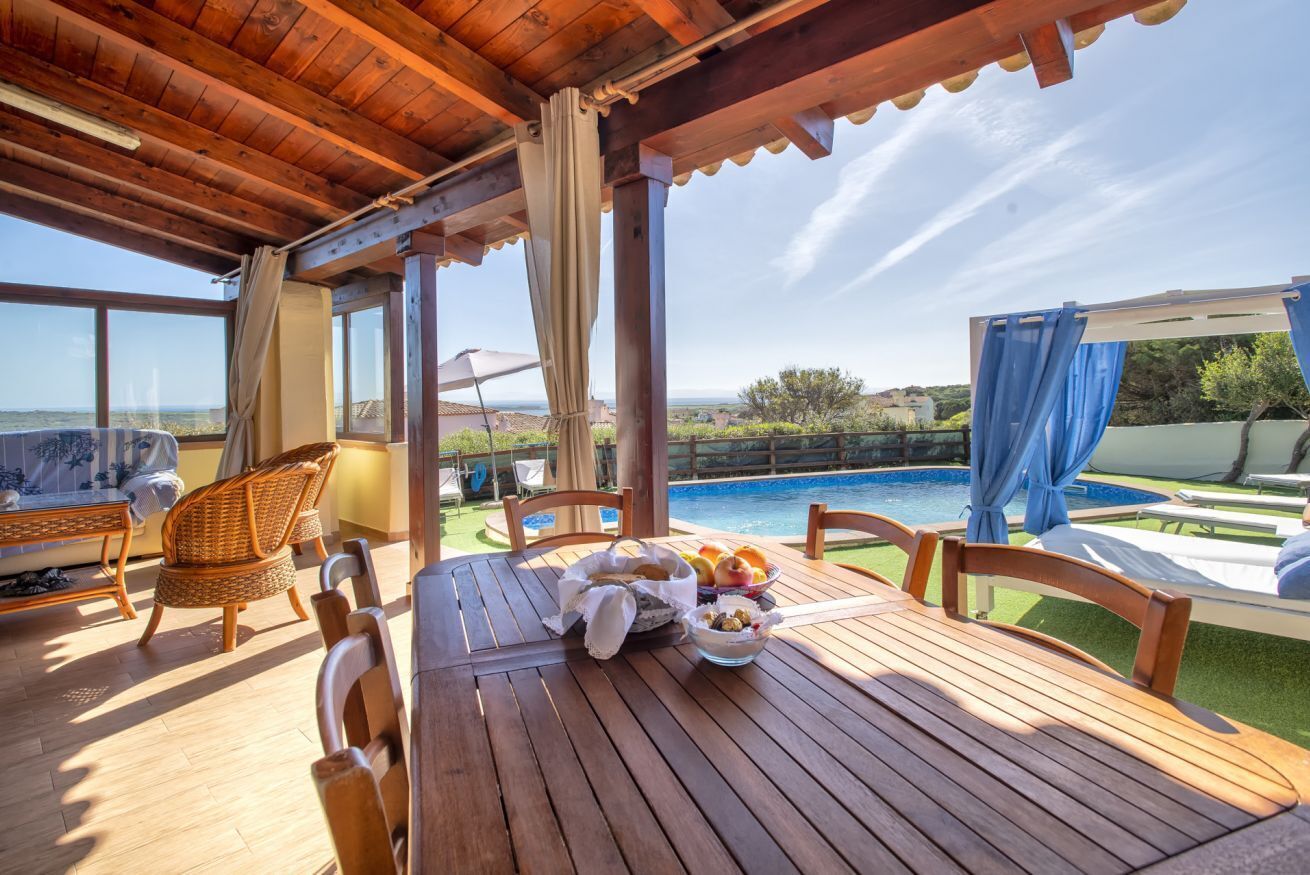 Una terraza de madera con una mesa, sillas y una piscina.