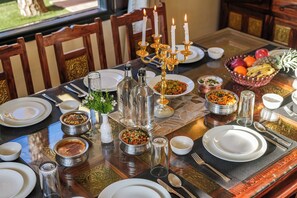 Une table à manger dressée avec différents plats, un chandelier et un panier de fruits.
