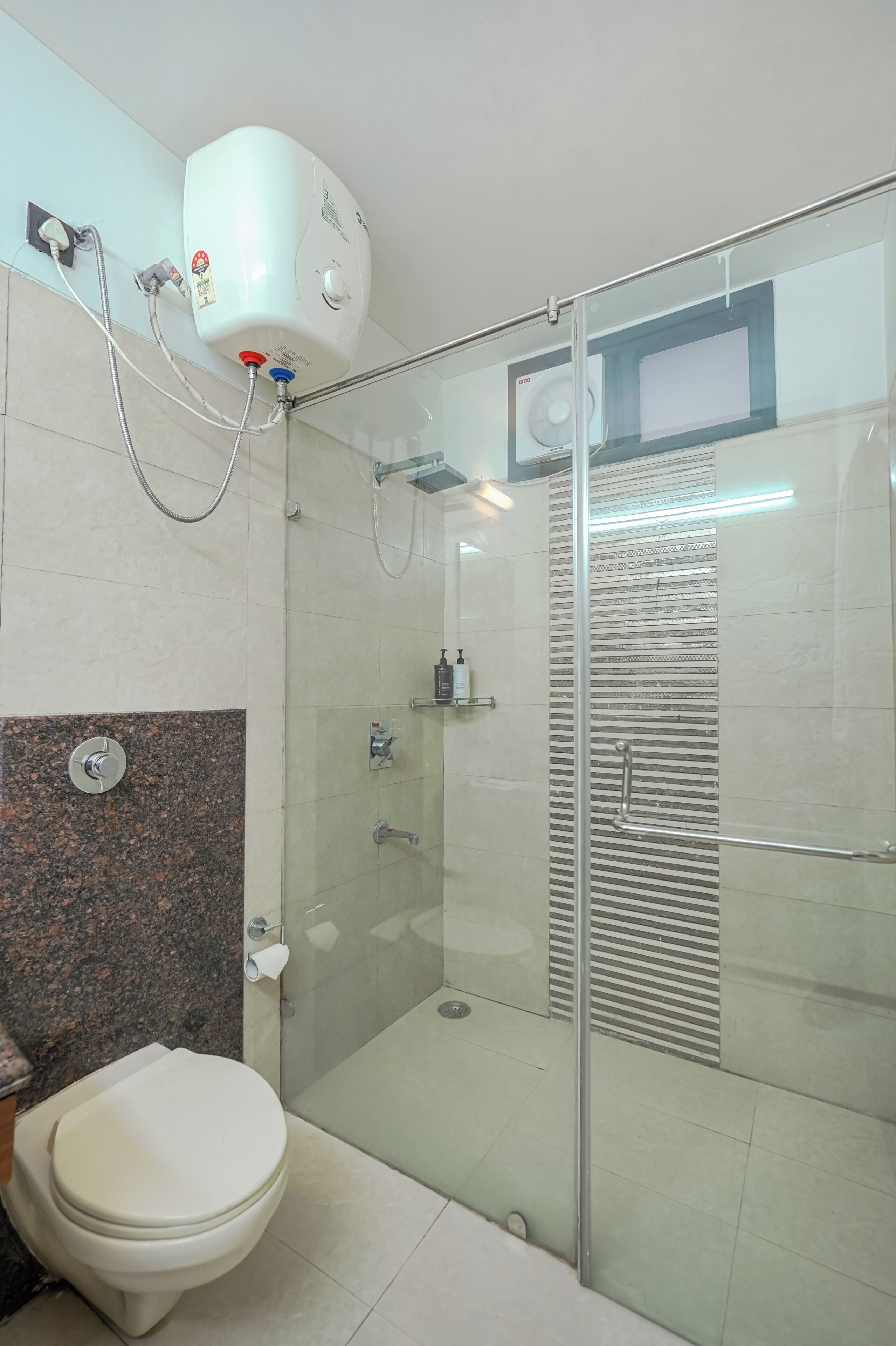 Un bagno moderno con WC, doccia e cabina doccia in vetro.